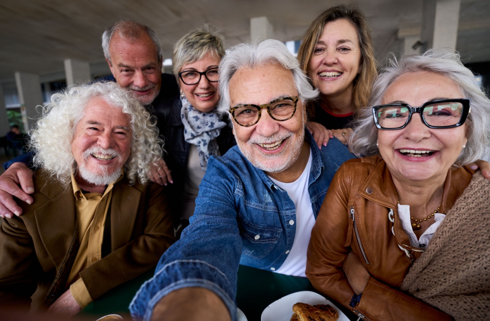A group of smiling and laughing seniors crowd in to take a selfie together, happy to have made friends in senior living