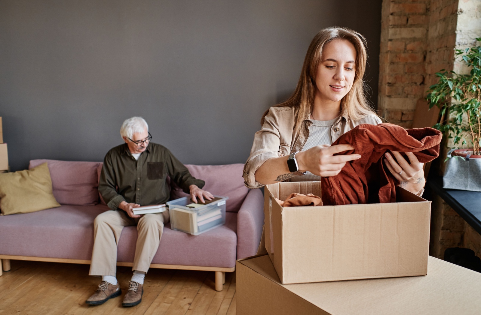 An adult grandchild goes through boxes of gifted clothes from a nearby grandparent as part of a downsizing process