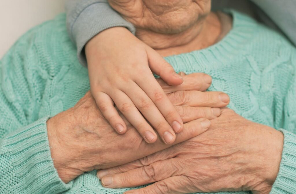 Close-up of a senior's hands with a young child's hands reaching in support